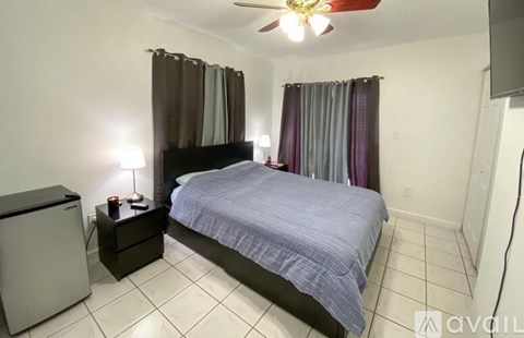 A bedroom with a bed, nightstand, and a ceiling fan.