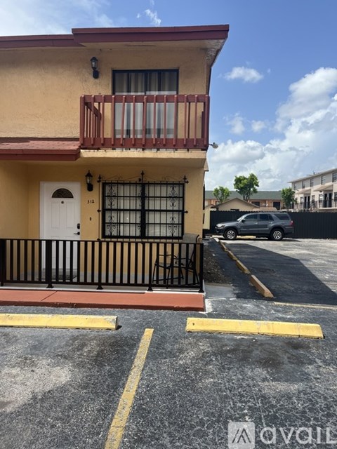A yellow building with a white door and a balcony with a black railing.