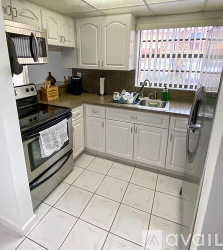 A kitchen with white cabinets and a black stove top oven.