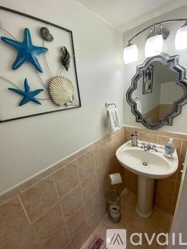 A bathroom with a starfish and seashell decoration on the wall.