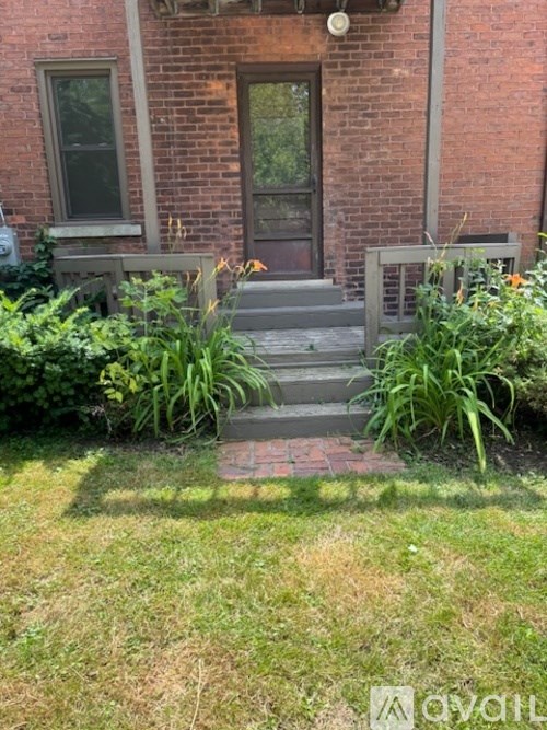 A brick house with a grey door and steps leading up to it.
