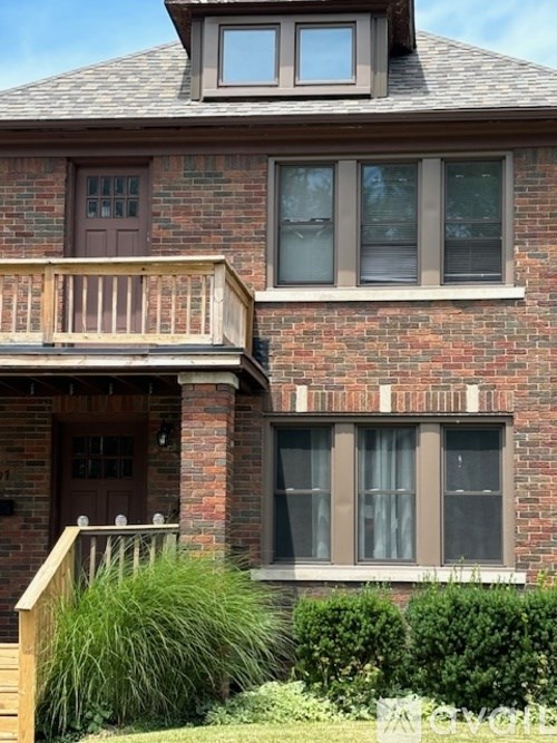 A red brick house with a balcony and a window.