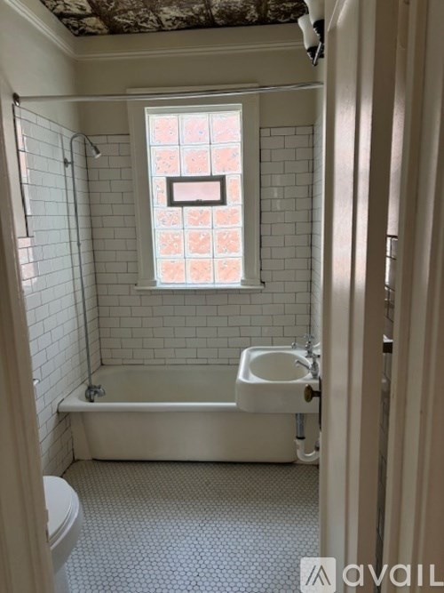 A bathroom with a white tub, sink, and tiled walls.