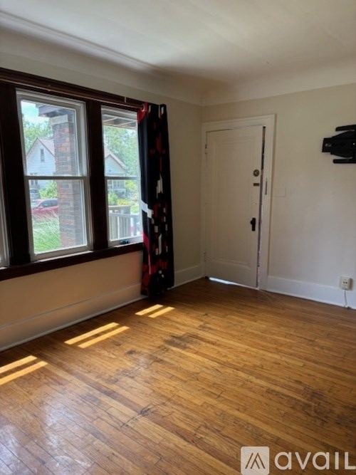 A room with wooden floors and a window overlooking a backyard.