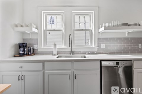 A kitchen with a stainless steel dishwasher and white cabinets.