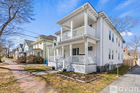A white two-story house with a balcony on the second floor.