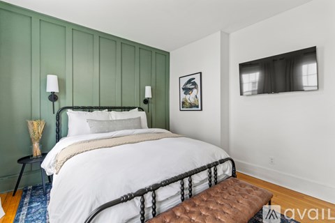 A bedroom with a white bed and a brown bench in front of it.