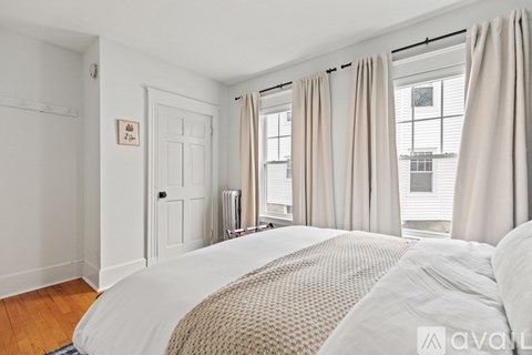 A bedroom with a large bed and a window with curtains.
