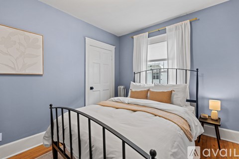 A bedroom with a bed, a nightstand, and a window.