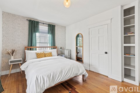 A bedroom with a large bed, a mirror, and a wooden floor.