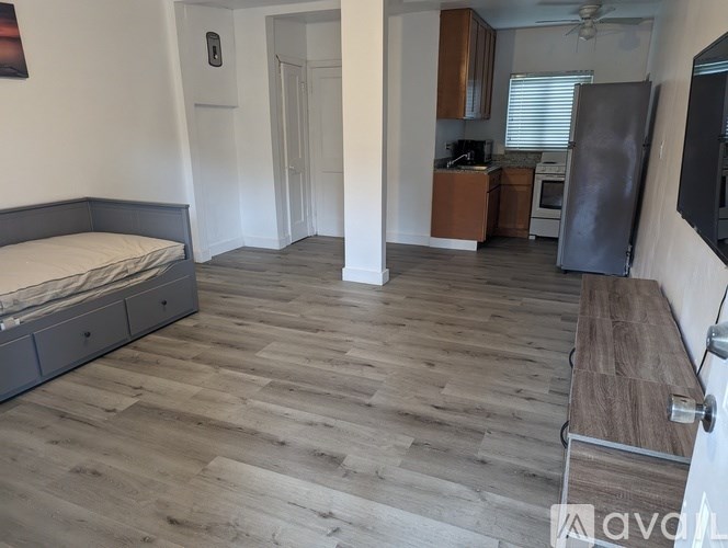 A room with wooden flooring and a bed on the left side.