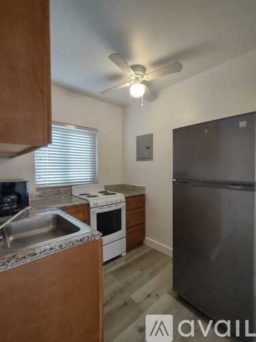 A kitchen with a stainless steel refrigerator, a sink, and a stove top oven.