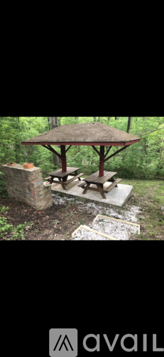 A wooden table is set up under a thatched roof in a garden.