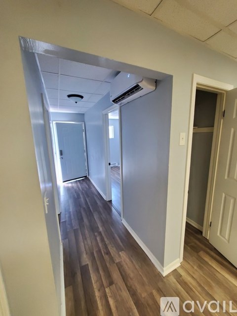 A hallway with wood flooring and white walls.