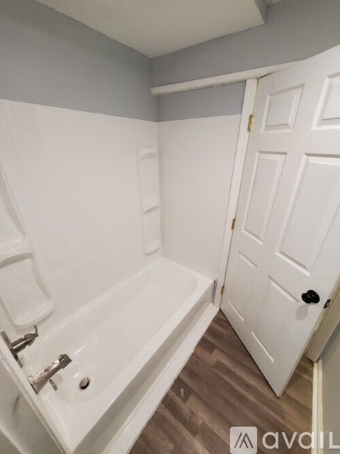 A white door is in a bathroom with a white tub.