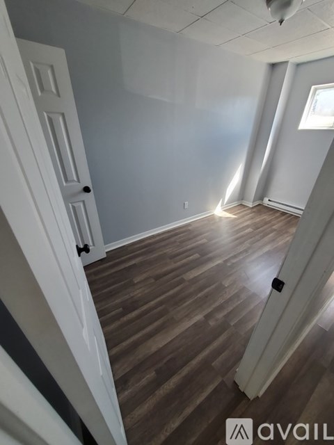 A room with wooden flooring and white walls.