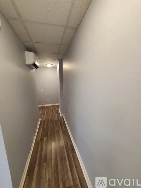 A long hallway with wood flooring and white walls.