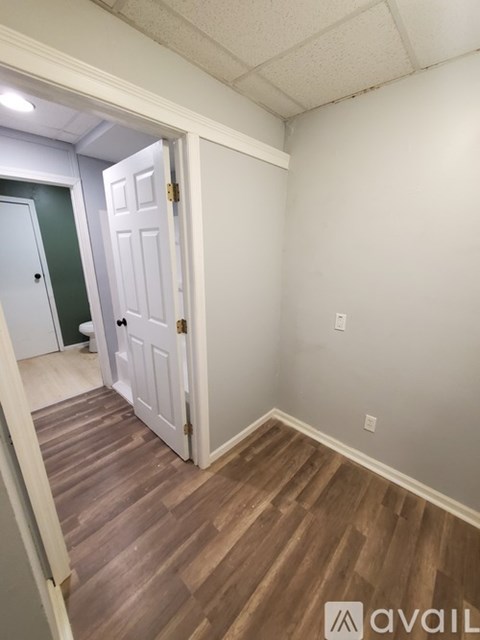 A room with a white door and wooden flooring.