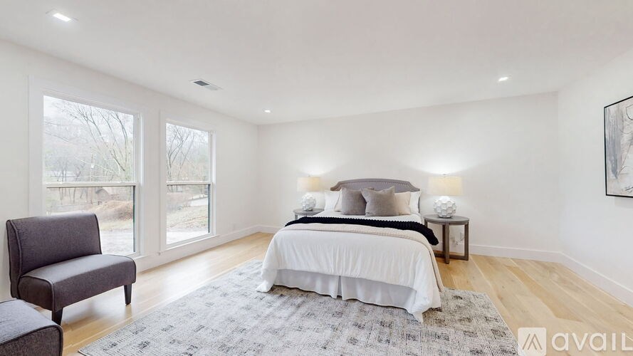 A bedroom with a large bed, a chair, and a painting on the wall.
