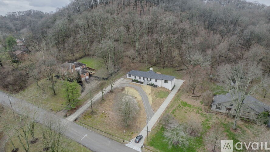 A bird's eye view of a property with a house surrounded by trees and a driveway.