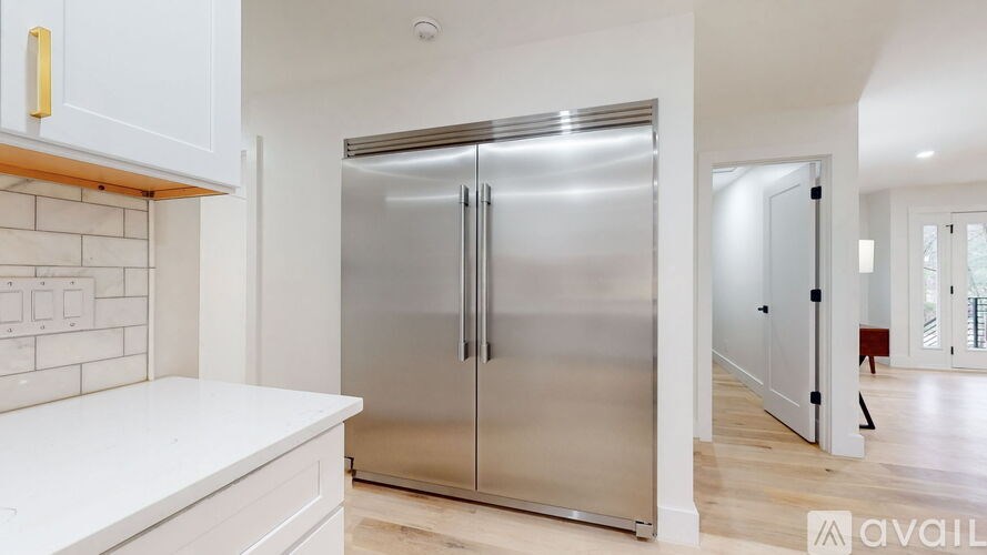 A stainless steel refrigerator in a kitchen with white cabinets.