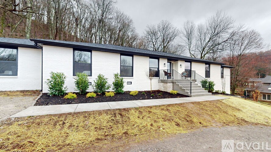 A white house with a black roof and a small garden in front.