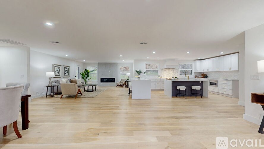 A spacious open-plan living and kitchen area with wooden flooring and modern furnishings.
