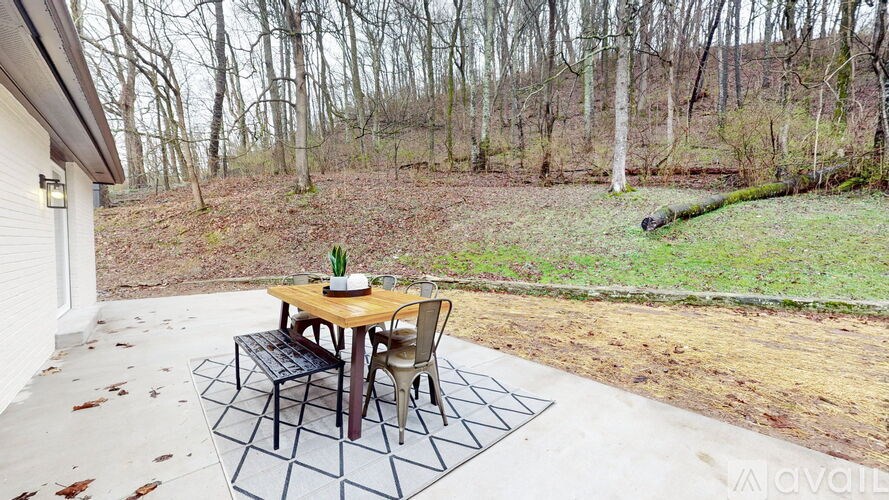 A patio with a table and chairs is surrounded by a forest.