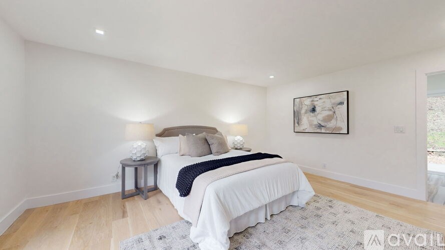 A bedroom with a large bed and a painting on the wall.