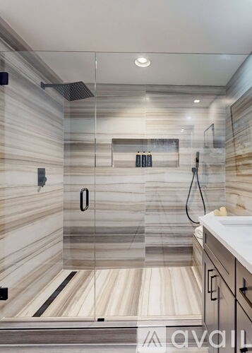 A modern bathroom with a glass shower stall and a white sink.