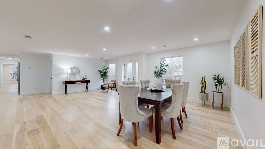 A dining room with a table set for six with white chairs.