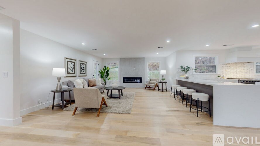 A modern living room with a fireplace and a kitchen area in the background.