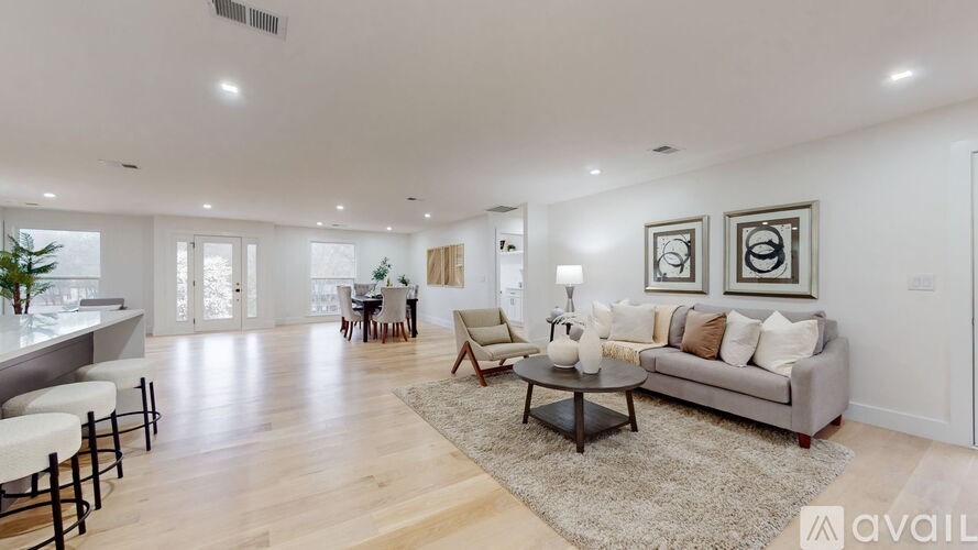 A spacious living room with a grey sofa, a coffee table, and a rug in the center.