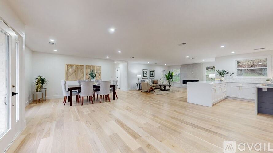A spacious open-plan living and dining area with wooden flooring and white walls.