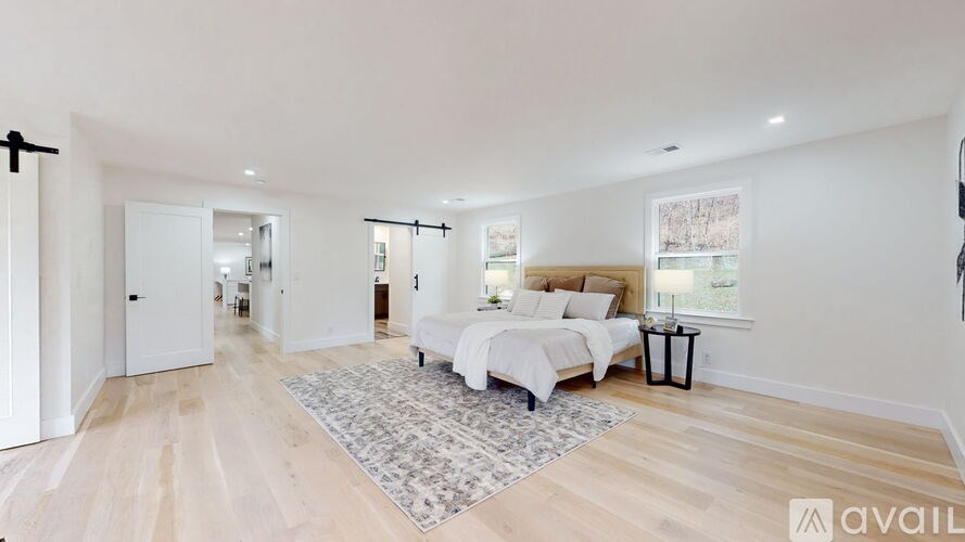 A bedroom with a large bed and a rug in the center.