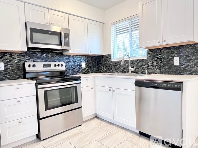 A kitchen with white cabinets and a black countertop.