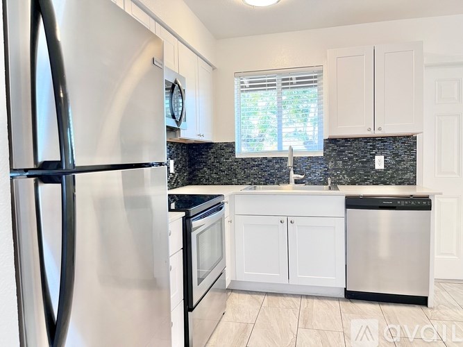 A modern kitchen with a stainless steel refrigerator and white cabinets.