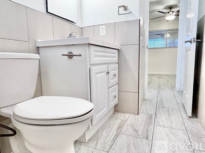 A white toilet sits next to a white cabinet in a bathroom.