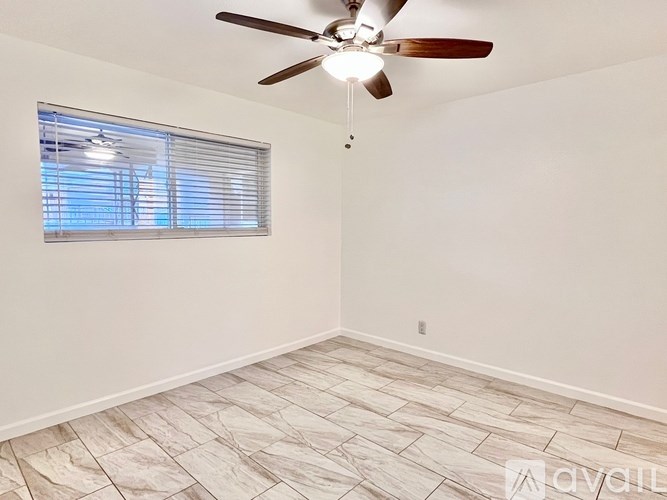 A room with a ceiling fan and a window with blinds.