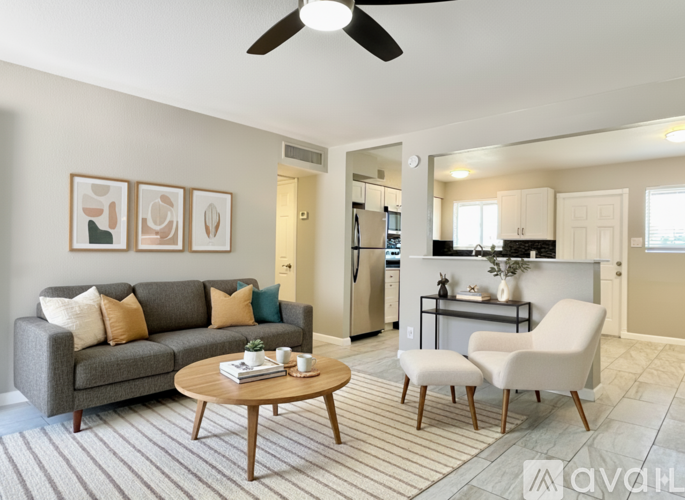 A living room with a grey couch, a coffee table, and a ceiling fan.