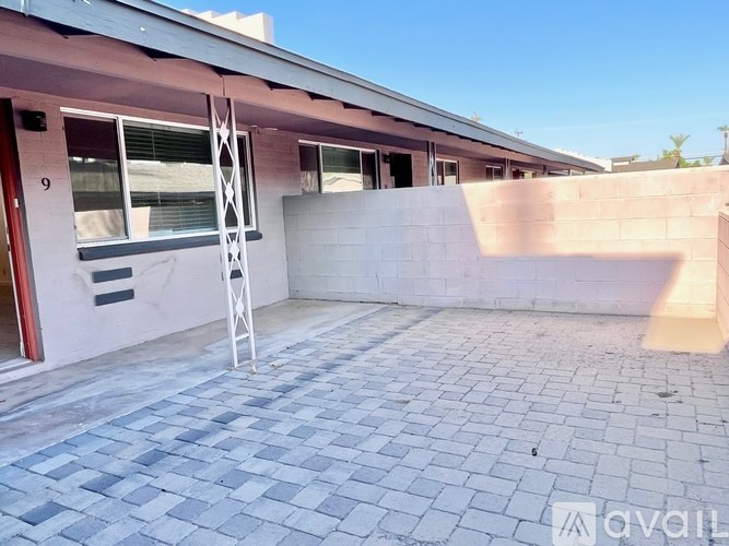A patio area with a brick patterned floor and a white ladder.