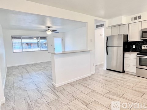 A kitchen with white cabinets and a black fridge.