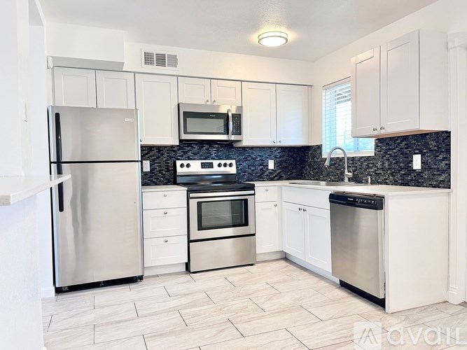 A kitchen with white cabinets and a black countertop.