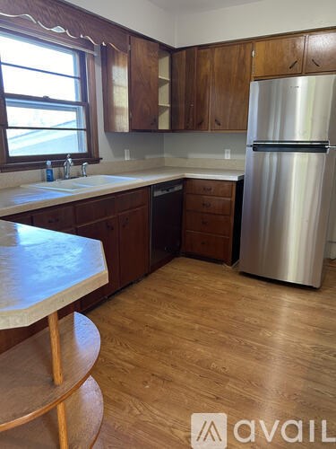 A kitchen with wooden cabinets and a stainless steel refrigerator.