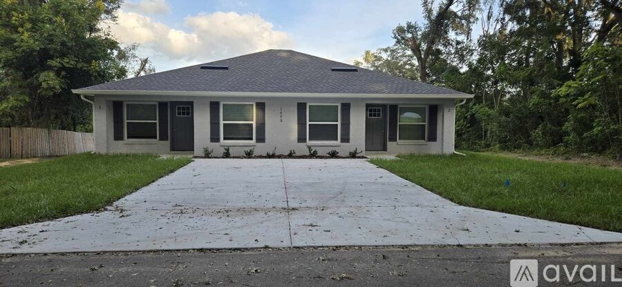 A house with a grey roof and a white fence is for sale.