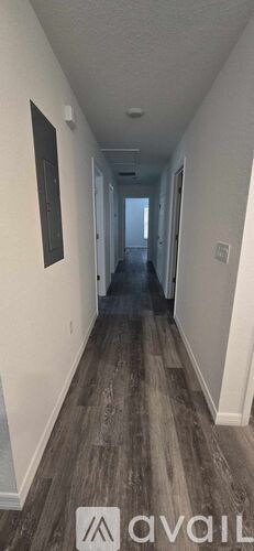 A long hallway with wood flooring and white walls.