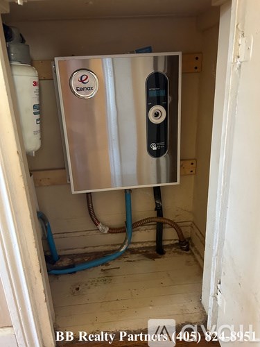 A tankless water heater is installed in a small, unfinished room.