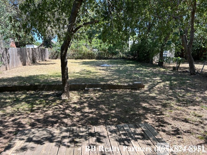 A backyard with a wooden deck and a tree.