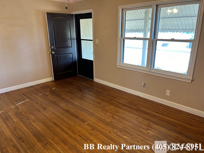 A room with a black door and a window with BB Realty Partners written on the floor.