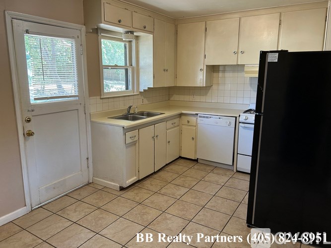 A kitchen with white appliances and cabinets.
